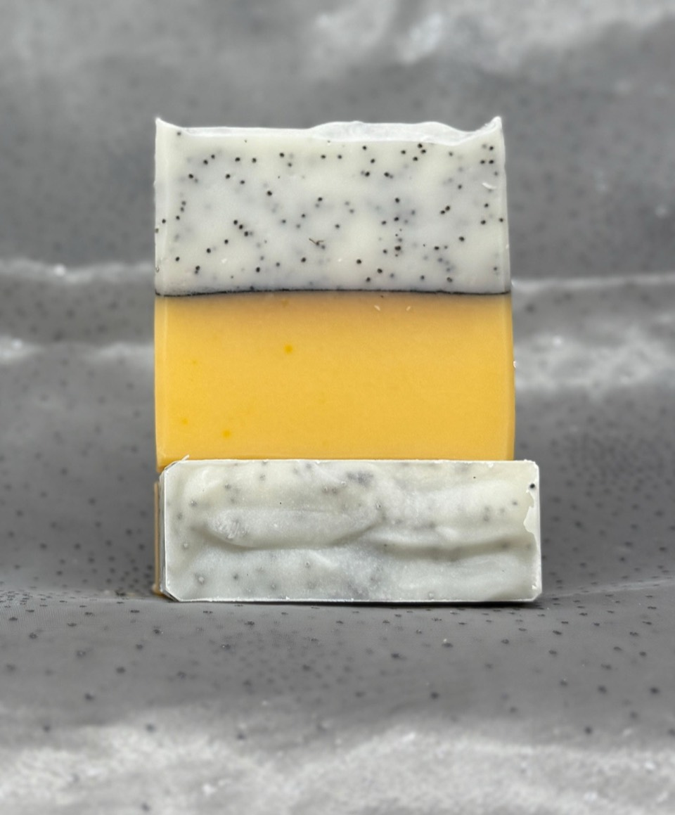 Lemon Poppy Seed soap: bar with a white, poppy-seed-speckled top over a bright yellow layer, a second bar lying in front